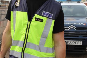 Agente de la Policía Nacional junto a un coche patrulla